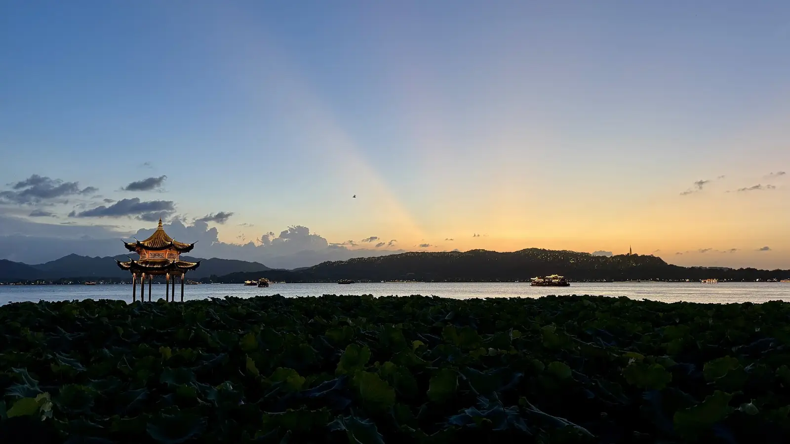 杭州西湖湖面与群山映照晚霞的摄影景观